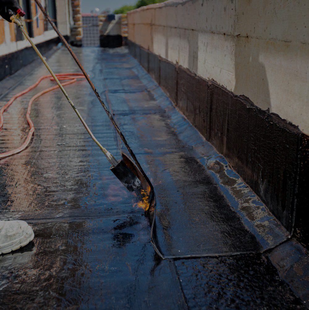 Applying waterproofing sealant on rooftop surface.