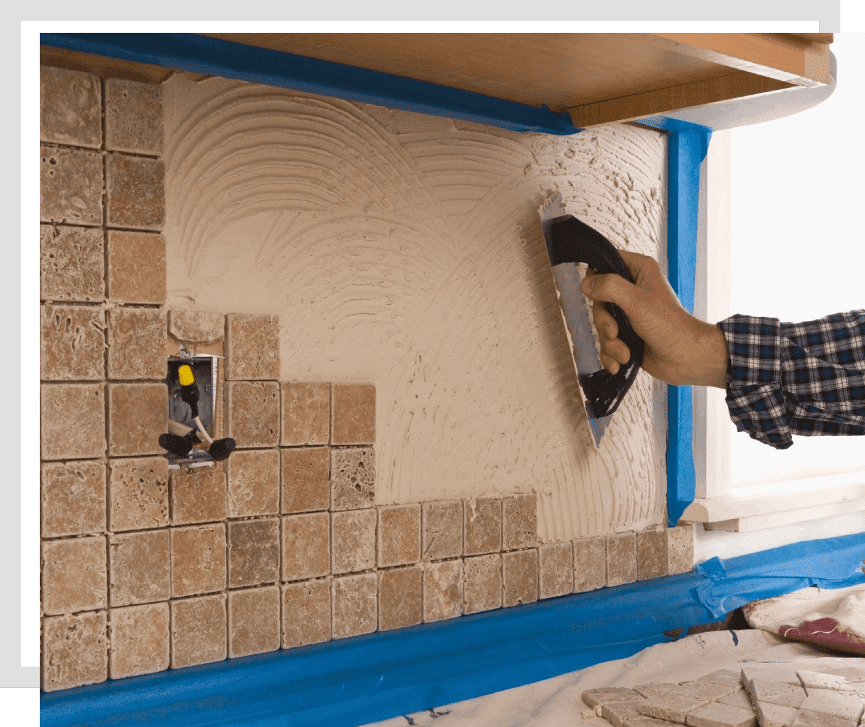 Hand applying adhesive to wall tiles during installation.
